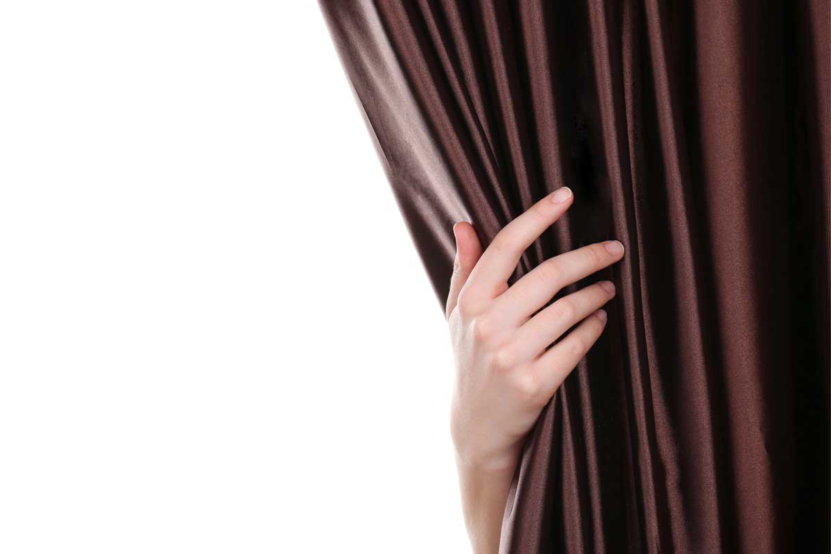 Hand touching a dark curtain on white background.