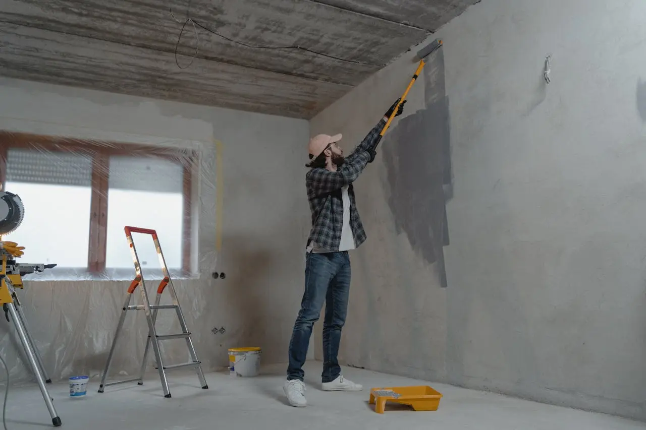 A man painting a room wall in a gray color, a room under renovation.