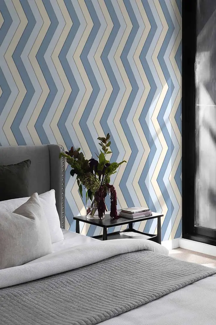 Image of The Striking Stripes wallpaper in the bedroom, featuring bold zigzag stripes in shades of blue and grey.