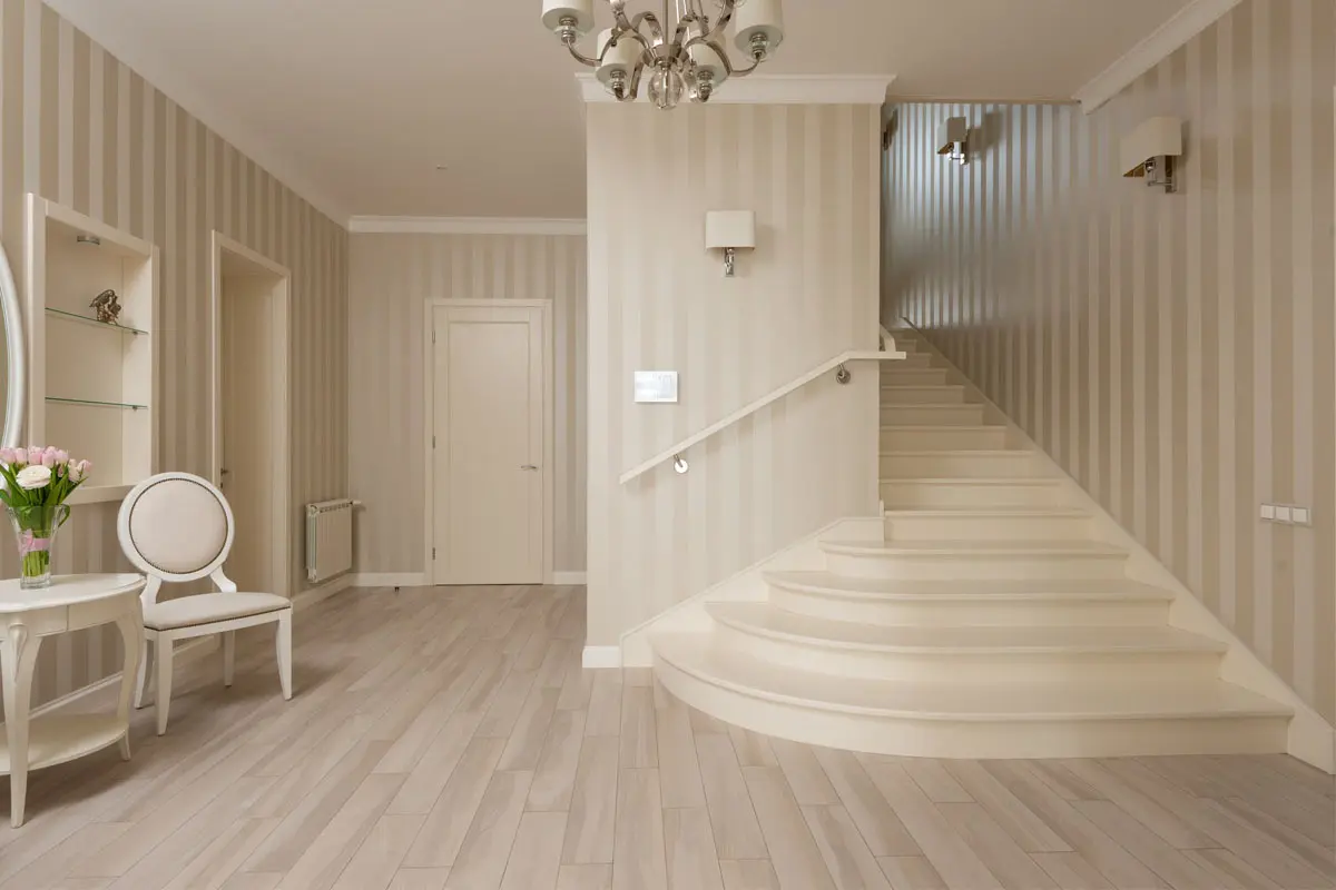 Elegant hallway with vertical striped wallpaper and a curved staircase.