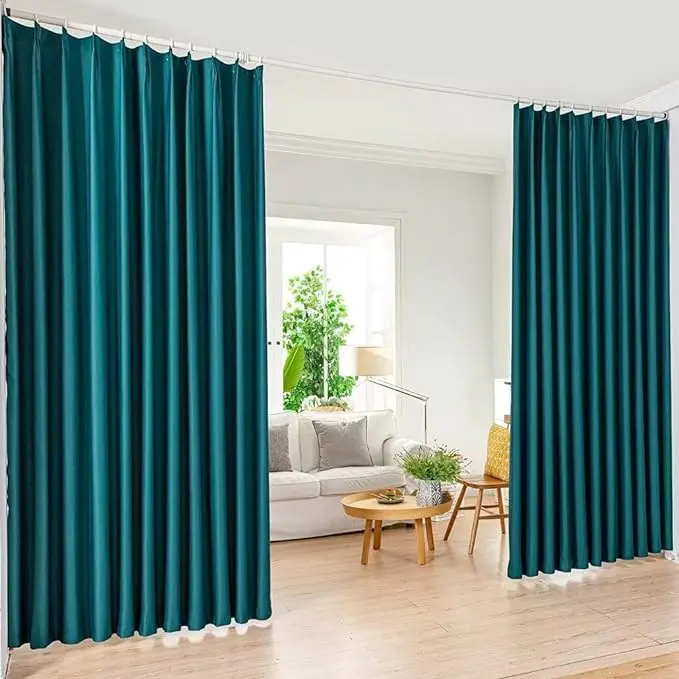 Green colored room divider curtains partially open to reveal a cozy living room with a sofa and plants.