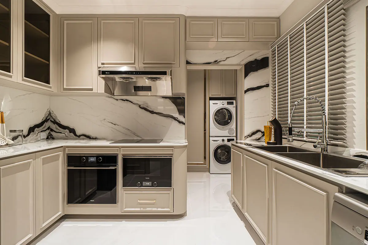 Modern kitchen with marble countertops and backsplash, sleek cabinets, integrated appliances, and a compact laundry area.