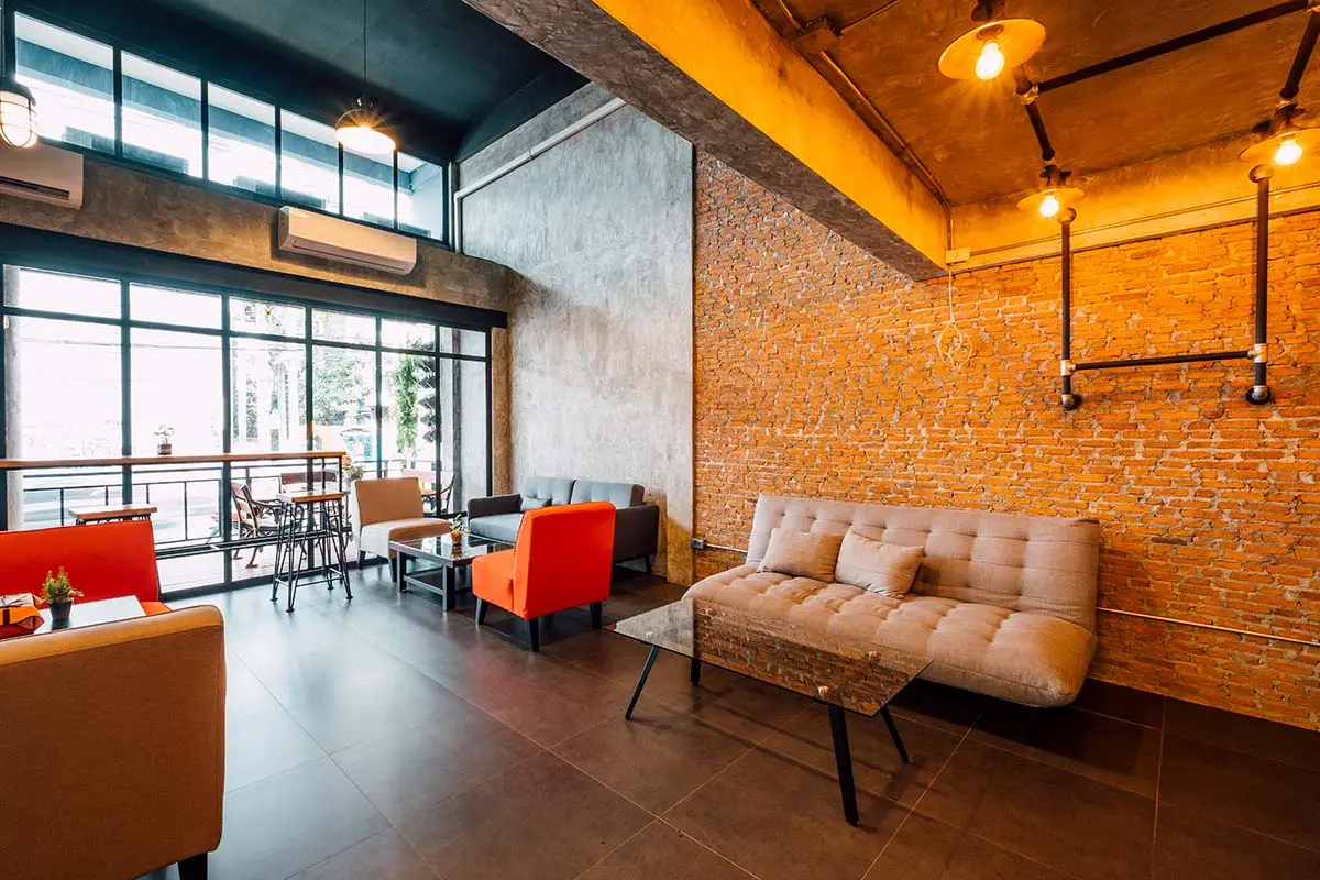 Loft-style cafe with brick and concrete pattern wallpapers, large windows, modern furniture, and industrial lighting.