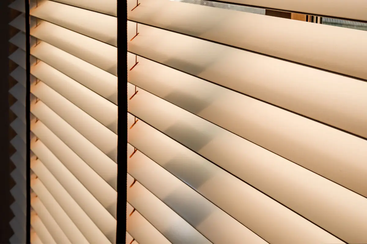 Close-up of wooden blinds with sunlight filtering through.