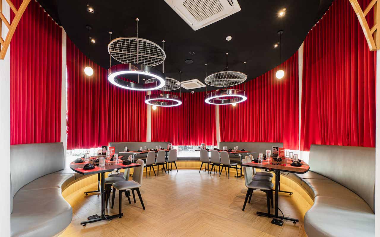 Restaurant with Circular Windows Draped in Red Curtains.