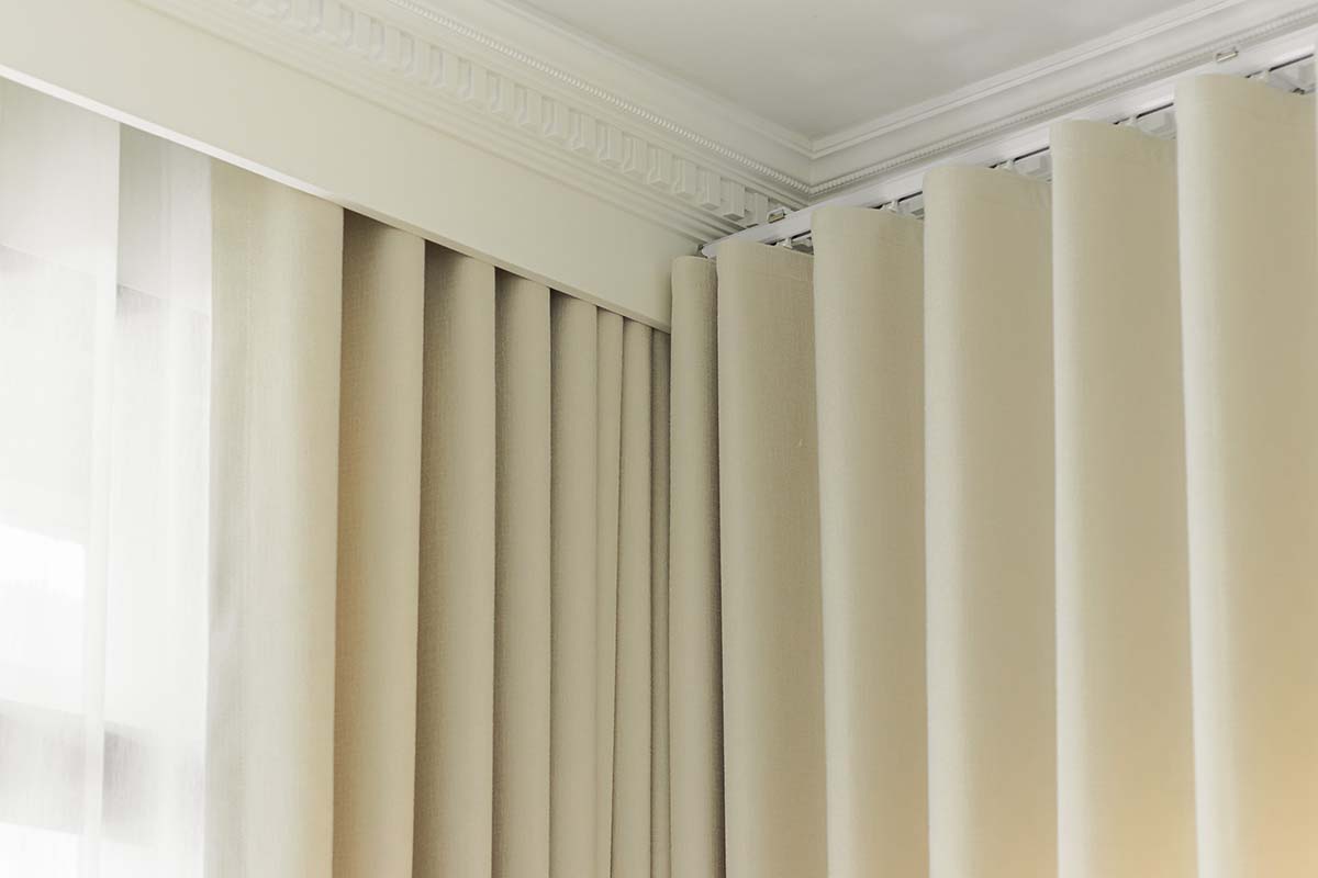 Layered curtains with sheer and dimout panels in a corner of the room.