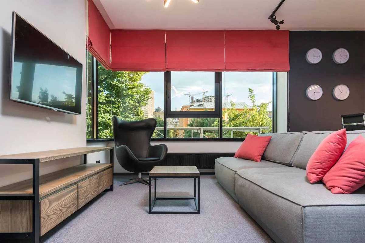 Living room with red color roman shades covering the window