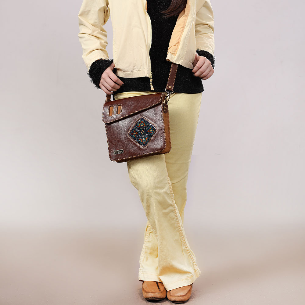 Woman wearing a brown crossbody bag with diamond woven carpet.