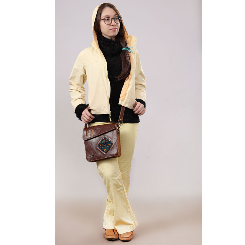Woman in cream outfit wearing brown crossbody bag.