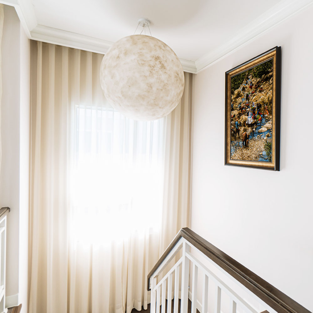 Cream Curtains with Globe Light Fixture and Framed Wall Carpet.